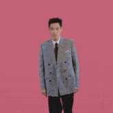 a man in a suit and tie on a pink background