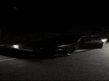 a car is parked on the side of the road at night with the door open