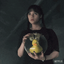 a woman is holding a ball with a yellow rubber duck inside of it and a netflix logo in the corner