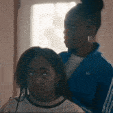 two girls are standing next to each other and one of them is wearing an adidas jacket .