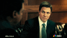 a man in a suit and tie is talking to another man with #suitsla written on the bottom