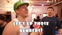 a man in a green hat says let 's up those numbers while standing next to another man