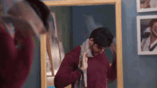 a man is looking at himself in a mirror with a towel around his neck