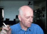 a bald man in a blue plaid shirt is smoking