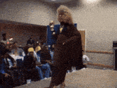 a woman in a brown coat is walking down a ramp