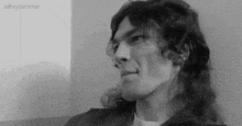 a black and white photo of a man with long curly hair .