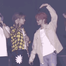 a group of people are standing on a stage and one of them has a flower on his pants .