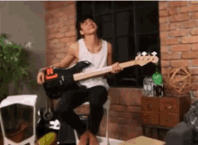 a young man is sitting on a chair playing a bass guitar .