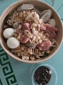 a bowl of food on a table with a cup of dipping sauce on the side
