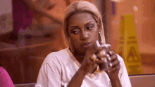 a woman is sitting at a table in a restaurant drinking a milkshake .