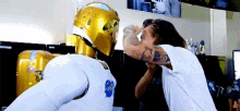 a man with a tattoo on his arm is standing next to a gold nasa robot