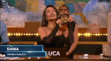a woman in a black dress is holding a trophy that says dania