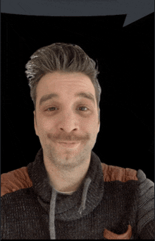 a man with a mustache wearing a sweater looks at the camera