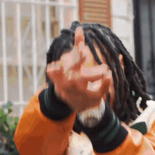 a man with dreadlocks is making a middle finger gesture