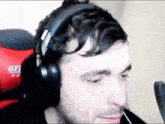 a man wearing headphones is sitting in a red gaming chair