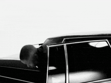 a black and white photo of a man in a black car