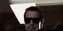 a man wearing sunglasses is standing in a dark room .