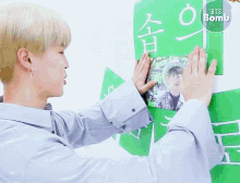 a person is holding a green sign that says bts bomb