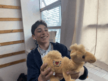 a boy is holding a stuffed camel that says " ohool " on it