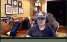 a man wearing headphones and a baseball cap is sitting in front of a microphone .