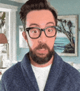 a man with a beard wearing glasses and a blue sweater