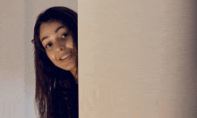 a woman peeking over a wall and smiling