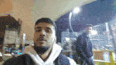 a man in a white hoodie is standing next to another man in a black jacket in front of a screen that says twitch