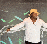 a man wearing a yellow hat is standing in front of a wall with a drawing of a tree on it