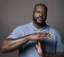 a man with a beard is wearing a blue shirt and making a stop sign with his hands .