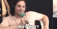 a man wearing headphones is holding a microphone and saying `` why not ? ''