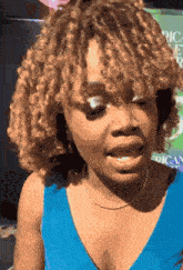 a woman with curly blonde hair is wearing a blue top