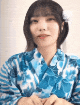 a woman wearing a blue and white floral kimono with a flower in her hair