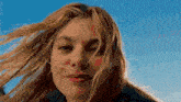 a close up of a woman 's face with a blue sky in the background