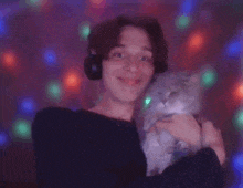a man with headphones is holding a cat in his arms .