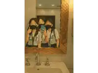 three girls wearing face masks are taking a selfie in a bathroom