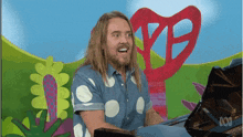 a man in a polka dot shirt is playing a piano in front of a sign that says abc