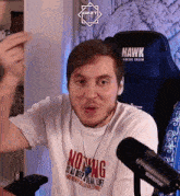 a man wearing a shirt that says nothing is as deep as real life stands in front of a shure microphone