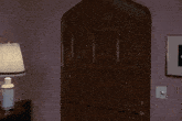 a man in a blue jacket stands in a doorway with a lamp