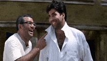 a man with glasses is pointing at another man 's neck