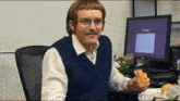 a man eating a sandwich in front of a computer screen that says google on it
