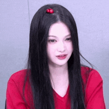 a woman wearing a red shirt has cherries in her hair