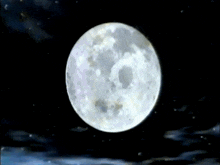 a full moon in a dark night sky with clouds