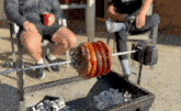 two men are sitting in chairs while a skewer of meat is being cooked