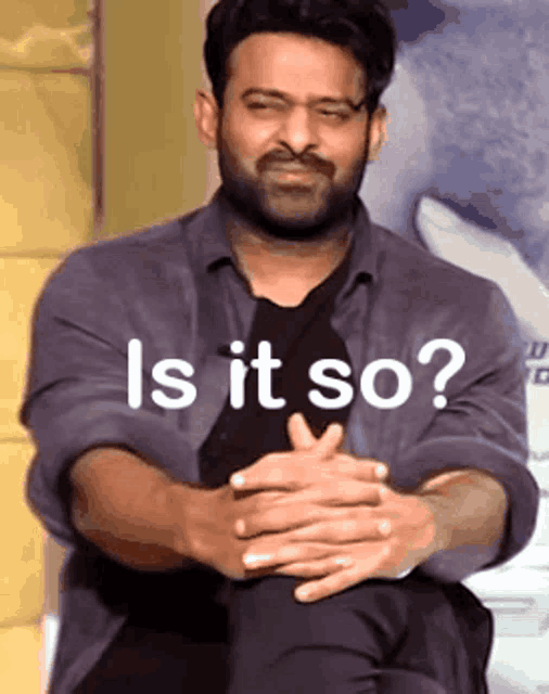 a man with a beard is sitting with his hands folded and the words 