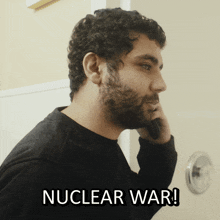 a man with a beard is talking on a cell phone and the words nuclear war are above him