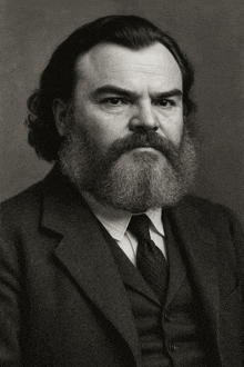 a man with a beard wearing a suit and tie looks at the camera
