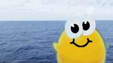 a cartoon character with big eyes and a smiling face is standing in front of the ocean