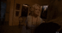 a woman is talking to another woman in a dark room with a lot of pictures on the wall .