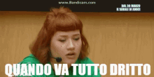 a woman with red hair is wearing a green shirt and a microphone and the words quando va tutto dritto are above her