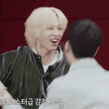 a man with blonde hair is laughing and hugging another man
